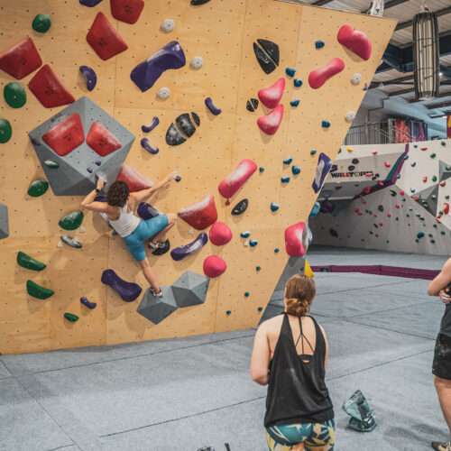 A group of friends watching a woman bouldering indoor