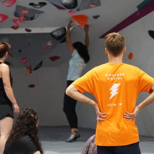A group of students standing in front of a bouldering wall.
