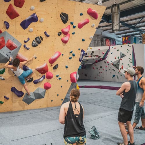 A group of people watching a woman boulder