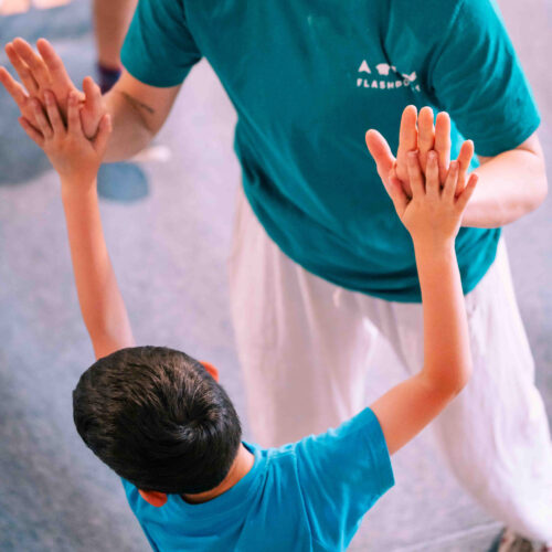 Boy giving a double high-five to a Flashpoint Easton coach after climbing on the bouldering wall