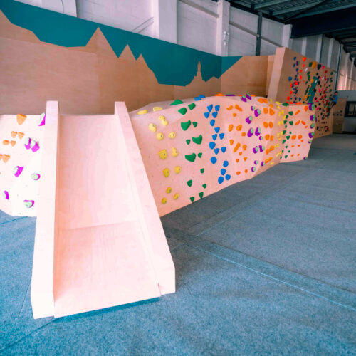 Wide view of the kids’ climbing area with a slide and colourful low bouldering walls at Flashpoint Easton